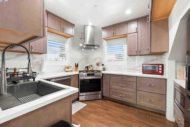 kitchen featuring sink, dark wood-type flooring, tasteful backsplash, stainless steel range with gas cooktop, and wall chimney exhaust hood