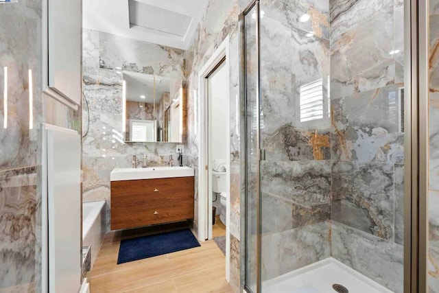 full bathroom featuring shower with separate bathtub, wood-type flooring, tile walls, vanity, and toilet