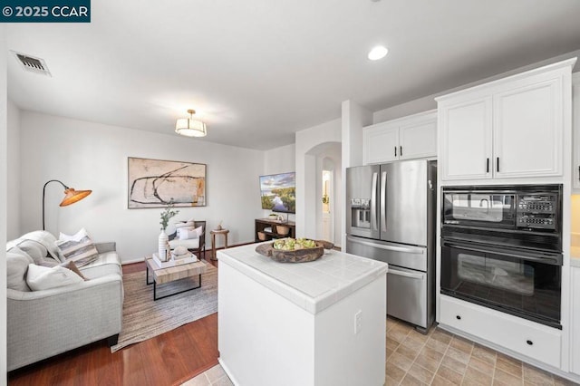 kitchen with white cabinets, black appliances, and tile countertops