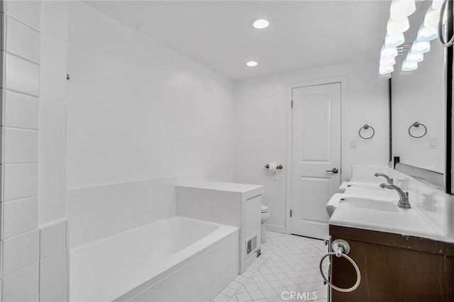 bathroom featuring tile patterned floors, vanity, a bathing tub, and toilet