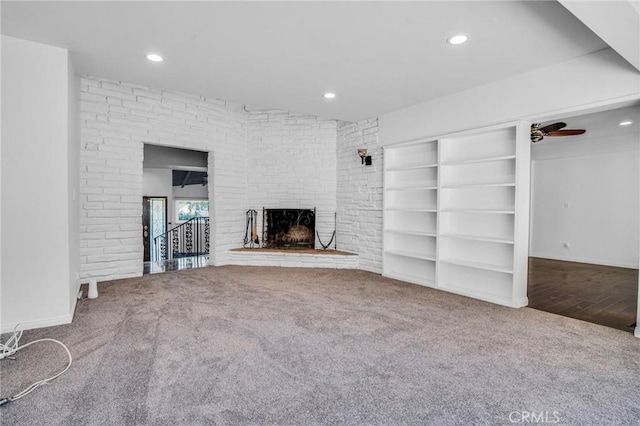 unfurnished living room featuring a fireplace, built in features, carpet flooring, and ceiling fan