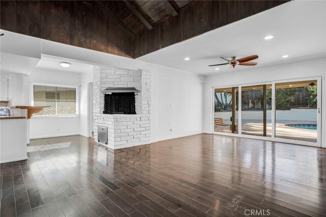 unfurnished living room with ceiling fan, plenty of natural light, and vaulted ceiling with beams