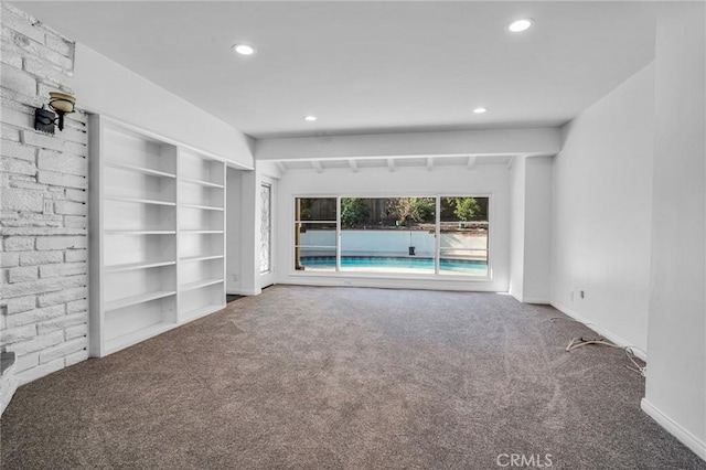 unfurnished living room featuring built in shelves and carpet flooring