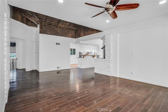 unfurnished living room featuring ceiling fan, dark hardwood / wood-style floors, and vaulted ceiling