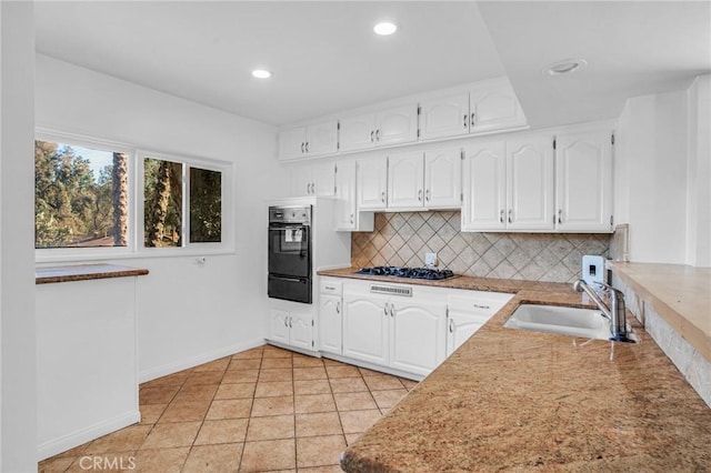 kitchen with stainless steel gas stovetop, white cabinetry, light tile patterned floors, decorative backsplash, and sink