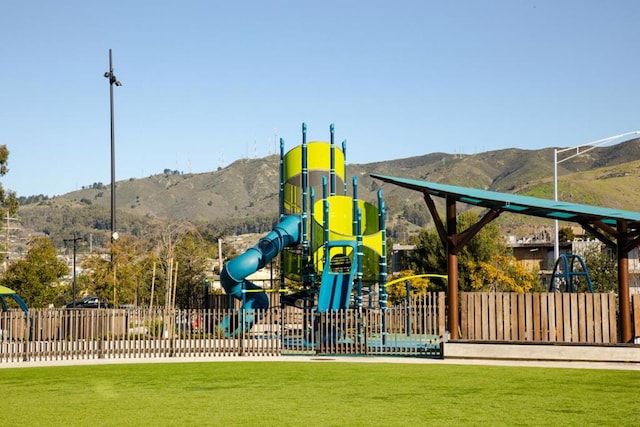 view of playground featuring a mountain view and a lawn