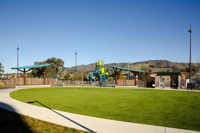 view of property's community with a mountain view, a lawn, and a playground