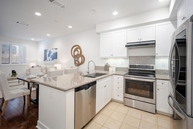 kitchen featuring sink, light stone counters, kitchen peninsula, stainless steel appliances, and white cabinets