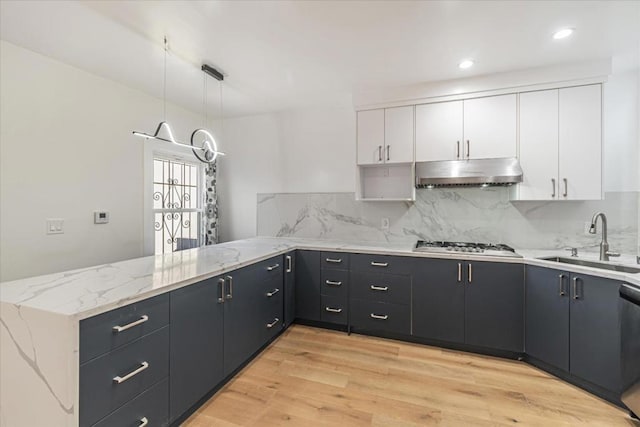 kitchen featuring decorative light fixtures, white cabinetry, light hardwood / wood-style floors, sink, and backsplash