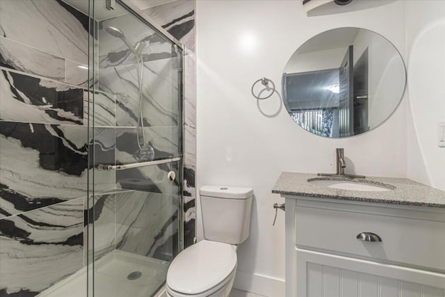 bathroom featuring vanity, toilet, and a shower with door