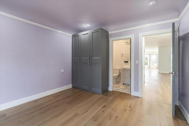 unfurnished bedroom featuring crown molding, light wood-type flooring, and connected bathroom