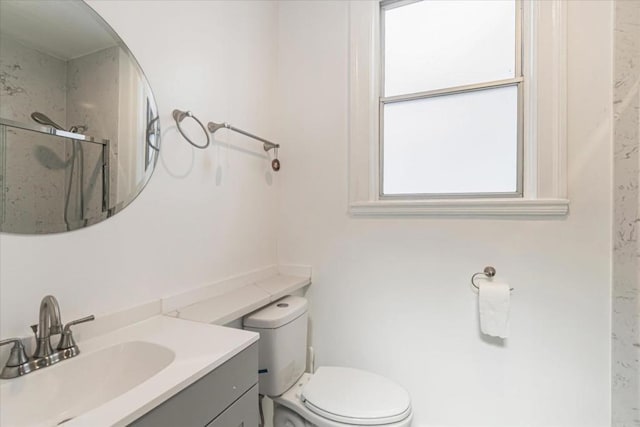 bathroom featuring toilet, an enclosed shower, and vanity