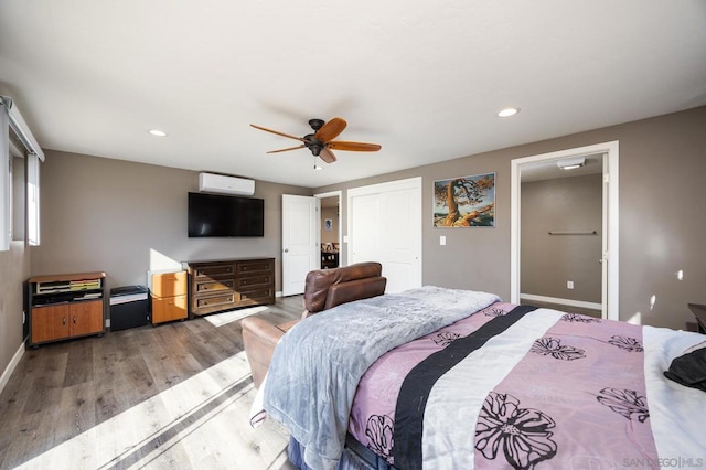 bedroom featuring hardwood / wood-style floors, an AC wall unit, and ceiling fan