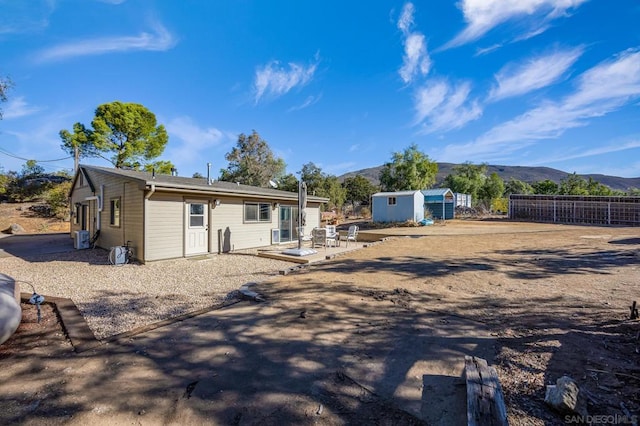 rear view of house featuring a mountain view, a patio, and a storage unit