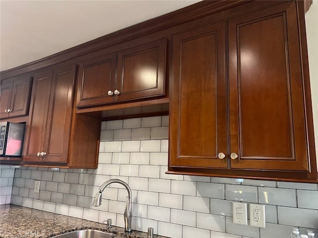 kitchen with sink, decorative backsplash, and dark stone counters