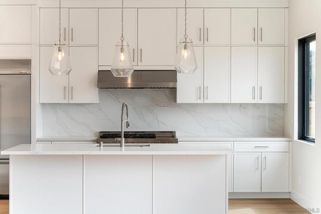 kitchen featuring decorative light fixtures, white cabinetry, tasteful backsplash, and built in fridge