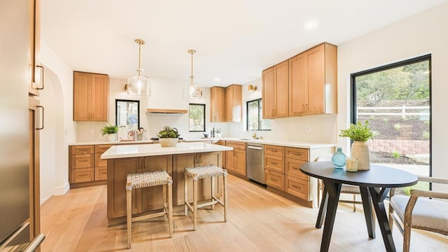 kitchen featuring pendant lighting, a center island, sink, light wood-type flooring, and stainless steel dishwasher