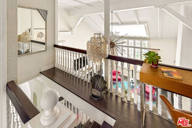 stairway featuring wood-type flooring, lofted ceiling with beams, and a notable chandelier