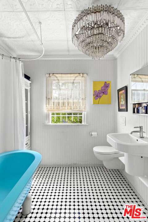 bathroom with toilet, walk in shower, and a notable chandelier