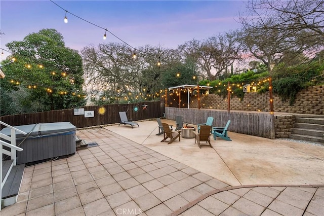 patio terrace at dusk with a hot tub and a fire pit