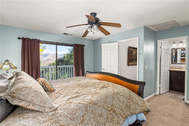 bedroom featuring ensuite bathroom, a textured ceiling, light carpet, access to outside, and ceiling fan