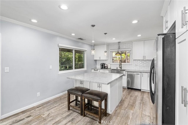 kitchen with pendant lighting, white cabinets, a kitchen bar, a kitchen island, and stainless steel appliances