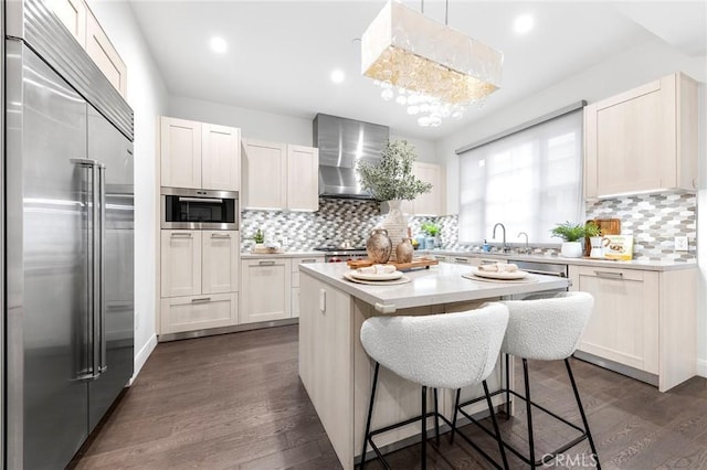 kitchen featuring white cabinetry, wall chimney range hood, a kitchen island, and appliances with stainless steel finishes