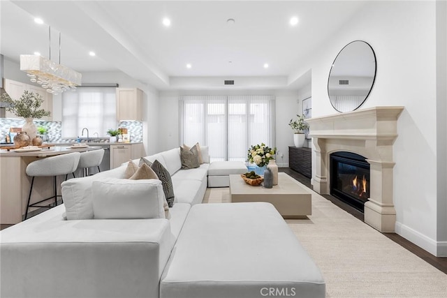 living room with sink, hardwood / wood-style floors, and a tray ceiling