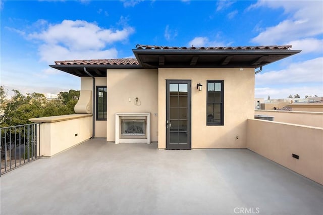 exterior space featuring an outdoor fireplace and a balcony