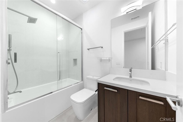 full bathroom with vanity, bath / shower combo with glass door, and toilet