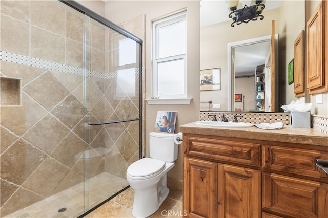 bathroom featuring vanity, a shower with door, and toilet