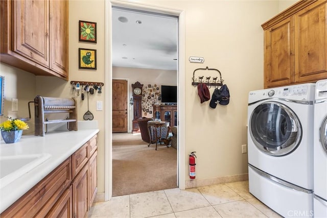 laundry area featuring washer and dryer, light tile patterned floors, and cabinets