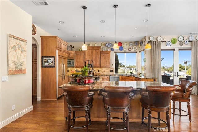 kitchen with hanging light fixtures, tasteful backsplash, dark hardwood / wood-style floors, and a kitchen bar