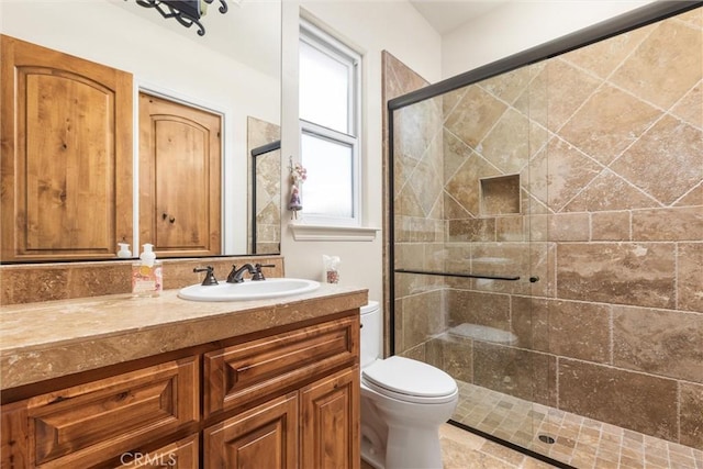 bathroom with a shower with door, vanity, and toilet