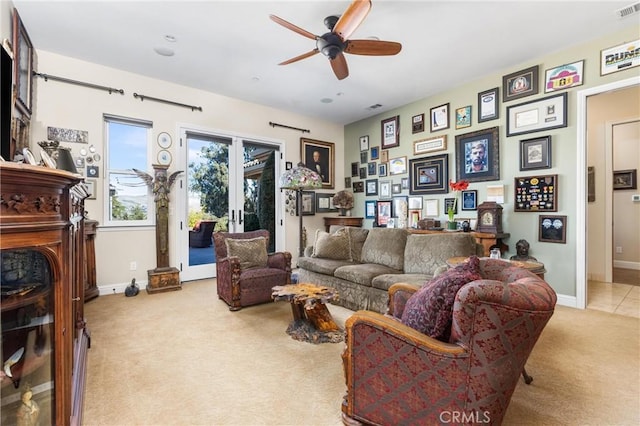 living room with french doors, ceiling fan, a fireplace, and light carpet