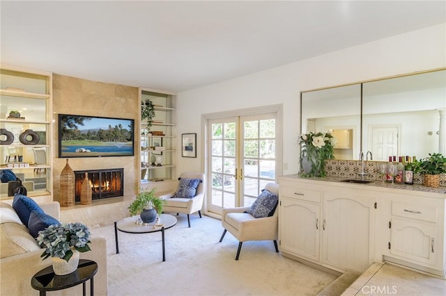 living room with sink, a tile fireplace, and french doors