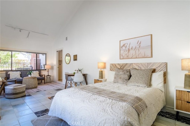 tiled bedroom featuring rail lighting and high vaulted ceiling