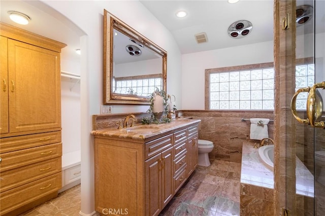 bathroom featuring vanity, a bathing tub, tile walls, and toilet