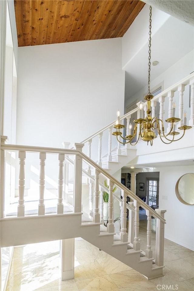 stairs with a towering ceiling, a chandelier, and wood ceiling