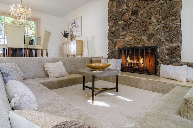 carpeted living room with a stone fireplace, ornamental molding, and a chandelier