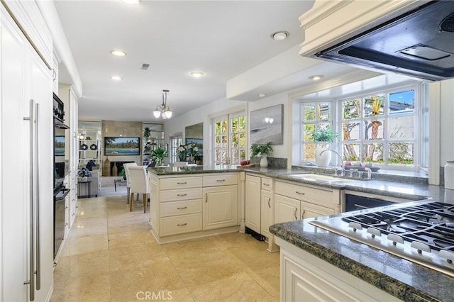 kitchen with stainless steel gas cooktop, sink, decorative light fixtures, plenty of natural light, and exhaust hood