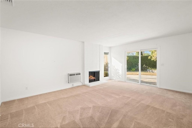 unfurnished living room featuring light carpet, an AC wall unit, and a brick fireplace