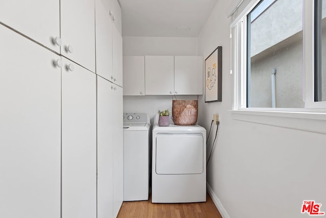 clothes washing area featuring light hardwood / wood-style floors, cabinets, and washer and clothes dryer