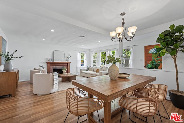 dining room featuring a notable chandelier, light hardwood / wood-style floors, and a fireplace