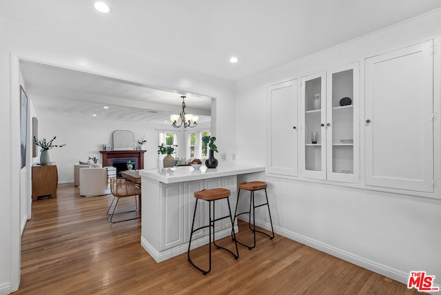 kitchen with a kitchen bar, white cabinets, kitchen peninsula, and light wood-type flooring