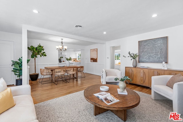 living room featuring a notable chandelier and light wood-type flooring