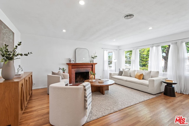 living room featuring light hardwood / wood-style flooring and a brick fireplace