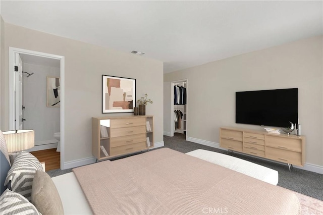 carpeted bedroom with a closet, a spacious closet, and ensuite bath