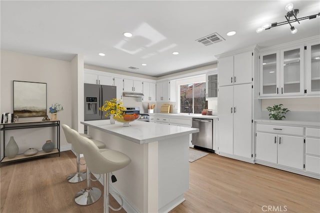 kitchen featuring white cabinets, appliances with stainless steel finishes, a center island, and light wood-type flooring