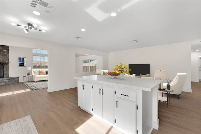 kitchen with white cabinetry, a kitchen island, and light wood-type flooring